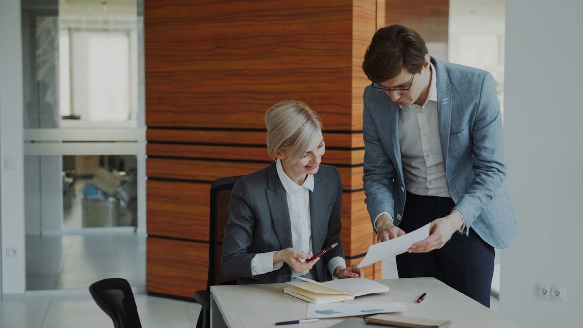 Two professionals in business attire reviewing documents at a desk